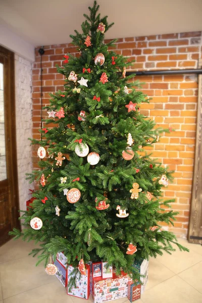 Rustic Christmas tree decorated with gingerbreads near brick wall