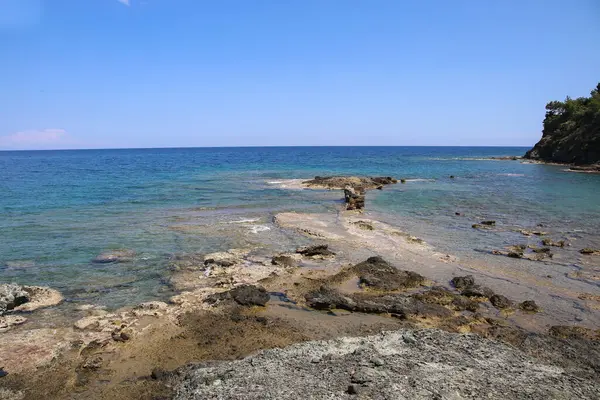 Güzel deniz ve gökyüzü ile kayalık kumlu sahil.