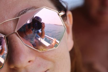 Bir mankenin güneş gözlüklü fotoğrafçısının yansıması.