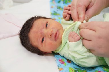 Siyah saçlı yeni doğmuş bebek kız kameraya bakıyor.