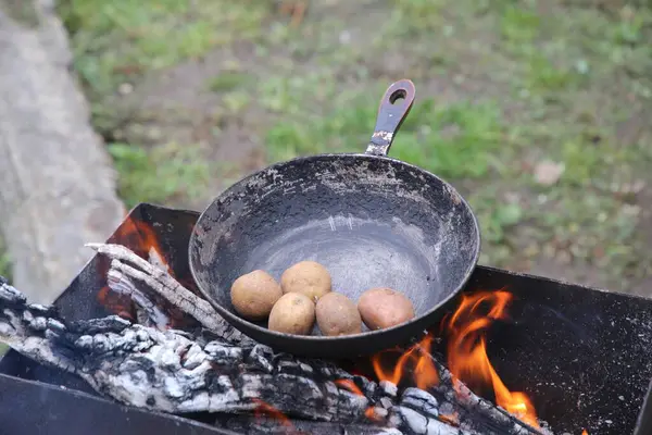 Kamp ateşinde patatesler cızırdıyor.