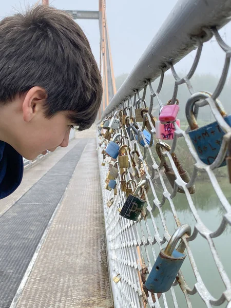 stock image Boy checking love locks bridge in Slovakia near Danube river. Ritual of affixing padlocks, as symbol of love, to bridge is spread in Europe from 2000s