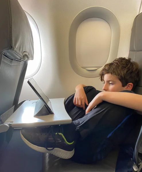 자세로 비행기를 여행하는 스러운 비행기 어린이와 비행기 여행중에 디지털 태블릿을 — 스톡 사진