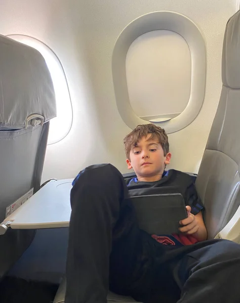 Симпатичний Хлопчик Відпочиває Лежачи Пасажирському Сидінні Літаку Спостерігаючи Дотиком — стокове фото