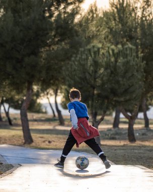 Çocuğun bacaklarının arasında futbol topuyla oynadığı arka manzara. Açık hava konseptinden keyif alıyorum..