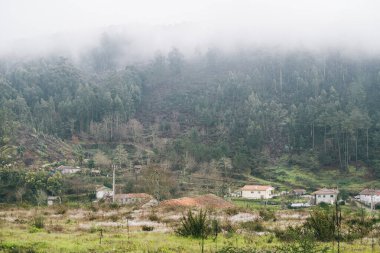 View of north Portuguese towns covered by clouds and surrounded by forest.
