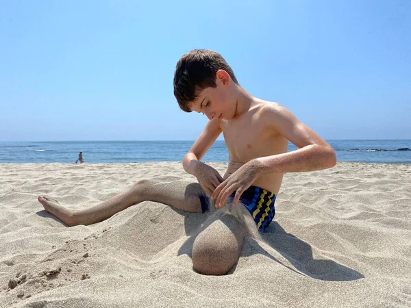 Παιδί Κάθεται Αμμώδη Παραλία Ρίχνει Άμμο Χέρια Του Πάνω Από — Φωτογραφία Αρχείου