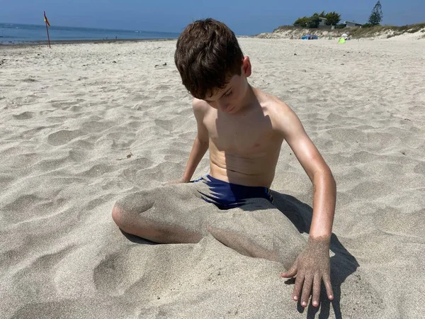 Bir Çocuğun Portresi Kumlu Sahilde Oturuyor Bacaklarını Kumla Örtüyor — Stok fotoğraf