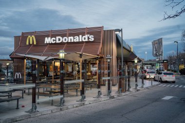 Alcobendas, Madrid, İspanya - 8 Mart 2023: Teras ile aydınlatılmış McDonalds Restoran cephesi ve akşamları araba kuyruğunda McAuto
