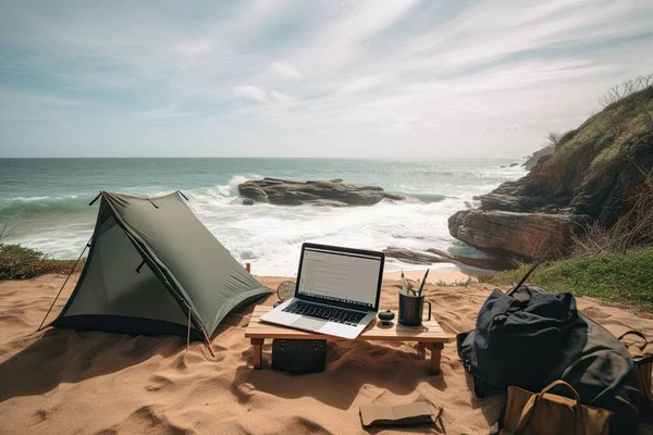 Laptop on wooden table and tent on tropical beach.Digital nomad and remote work concept