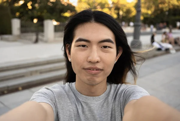 Selfie shot of young handsome chinese tourist male with confident expression while visiting Madrid city.