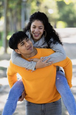 Gülümseyen genç bir çiftin portresi. Madrid 'de halka açık bir parkta sırtına binen bir adam..