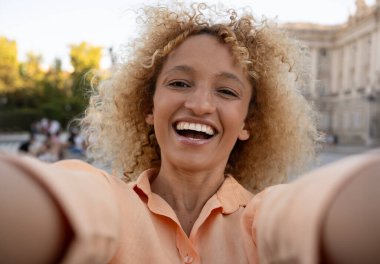 Güzel, pozitif kıvırcık saçlı, açık havada yaşayan Brezilyalı genç bir kadının selfie 'si..