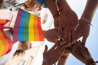 Bir grup insan el ele tutuşuyor ve gökkuşağı bayrağı taşıyor. Sahne, LGBTQ topluluğu için birlik ve desteklerden biridir..