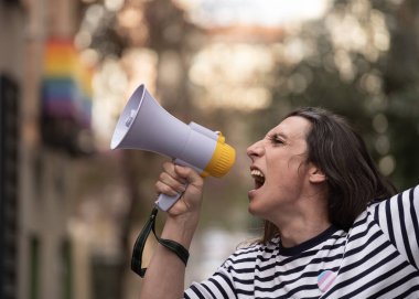 Transseksüel kadın elinde bir megafon tutuyor ve homoseksüel toplumsal ayrımcılığı protesto etmek için bağırıyor..