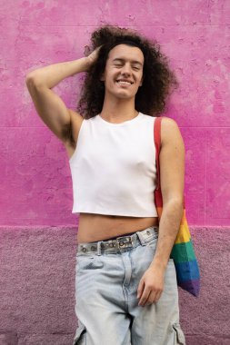 Pembe arka planda izole edilmiş kameraya gülümseyen şehvetli pozlu eşcinsel bir adam portresi..