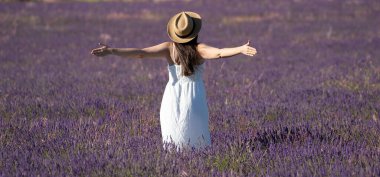 Beyaz elbiseli mutlu bir kadının, lavanta tarlasında kolları açık duruşu. Özgürlük ve mutluluk kavramları.