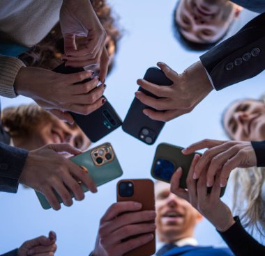 Bir grup insan cep telefonlarını daire şeklinde tutuyor. İnsanlar gülümseyip eğlenirken sahne neşeli ve eğlencelidir.