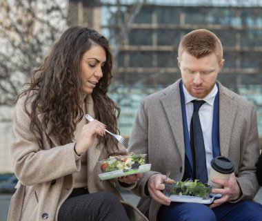 İş arkadaşları iş yerinde ciddi bir sorun tartışıyorlar ve molada dışarıda salata yiyorlar..