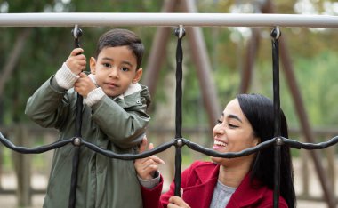 Mutlu bir anne ve oğulun oyun sahasında eğlenirken çekilmiş bir fotoğrafı..