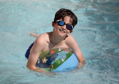 Havuzda şişme topla eğlenen genç bir çocuğun portresi..