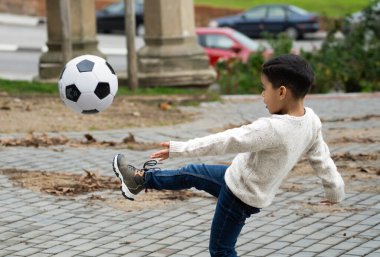 Dominikli küçük çocuk dışarıda futbol topuyla eğleniyor..