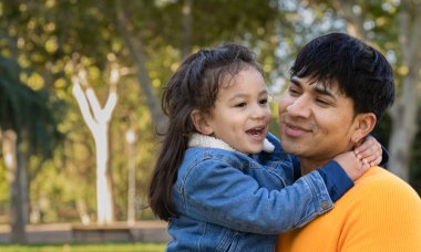 Mutlu İspanyol bir babanın oğluyla dışarıda fotokopi alanı olan bir parkta kucaklaşması ve gülümsemesi..
