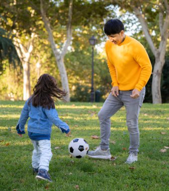 İspanyol, bekar bir babanın portresi. Parkta çocuğuyla eğleniyor. Futbol topuyla oynuyor..