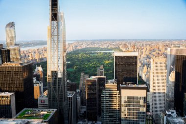 Manhattan, New York 'ta güneşli bir günde Central Park' ın gökdelenlerle çevrili görüntüsü.