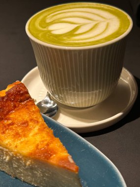 Matcha latte sanat tasarımı ve bir dilim yanık peynirli kek nefis bir kafe deneyimi yaratır.