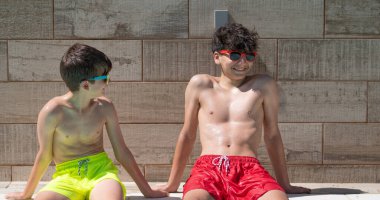 Mayolu iki genç erkek arkadaş havuz başında güneşli bir günün tadını çıkarıyorlar.