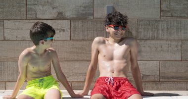 Mayolu iki genç erkek arkadaş havuz başında güneşli bir günün tadını çıkarıyorlar.