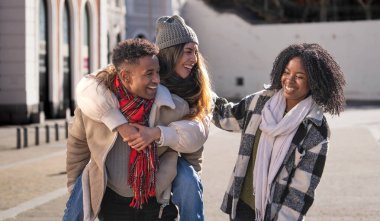 Çok ırklı arkadaşlar, kışın şehirde birlikte yürüyüp eğleniyorlar.