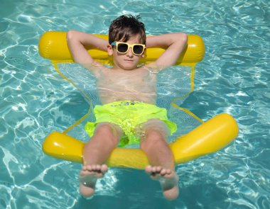 Havuzda güneşli bir günün tadını çıkaran bir çocuk.