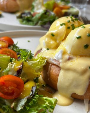 Sağlıklı ve tatmin edici bir branç için yanında salata ile Hollandaise soslu yumurtalı Benedict.