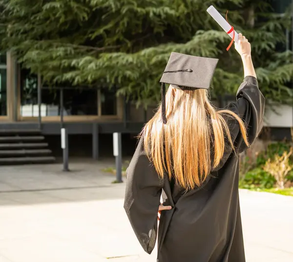 Diplomasını havada yükselten yüksek lisans öğrencisi, başarılı mezuniyetini kutluyor.