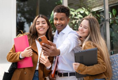 Dışarıda cep telefonuyla selfie çeken mutlu öğrenciler..
