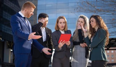 Stresli iş ekibi, şirket krizi ve mali sorunlar hakkında endişeli bir şekilde tabletten kötü haberler alıyor..