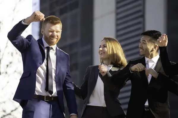 Ofis binalarının önünde başarılı bir projeyi kutlayan heyecanlı iş ekibi