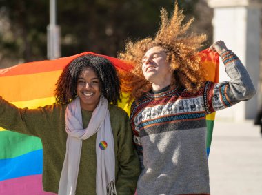 Gökkuşağı bayrağı taşıyan ırklar arası bir çift, aşkı, çeşitliliği ve lgbtq haklarını kutluyorlar.