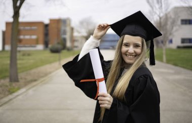 Mezuniyet töreninde gülümseyen ve diplomasını tutan genç bir mezun.