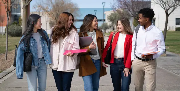 Kampüste yürüyüp sohbet eden çeşitli üniversite öğrencileri mutlu olsun.