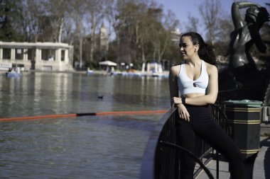 Genç sporcu kadın Madrid, İspanya 'daki Emeklilik Parkı gölünde egzersiz yaptıktan sonra dinleniyor.