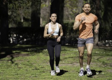 Parkta koşan ırklar arası bir çift fotokopi uzayı ile güneşli bir günde spor yapıyor..