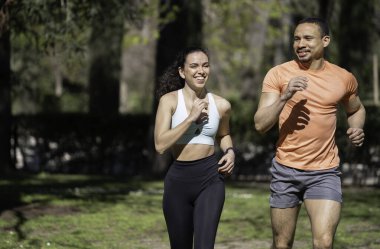 Çok ırklı genç bir çift parkta koşuyor, fotokopi alanlarıyla sağlıklı yaşam tarzlarının tadını çıkarıyorlar.
