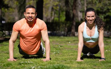 Atletik çift parkta şınav çekiyor, birlikte dışarıda çalışmaktan zevk alıyorlar.