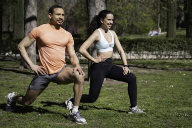 Atletik erkek ve kadın güneşli bir günde parkta ısınıyorlar..