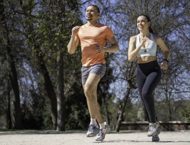 Çift parkta koşuyor, sağlıklı yaşam tarzının ve güneşli günün tadını çıkarıyor..