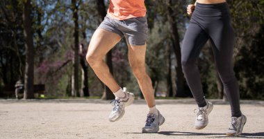 Güneşli bir günde spor giyerek parkta koşan bir çift..