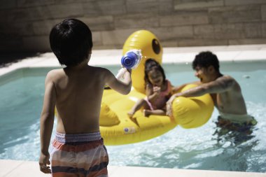 Latin ailesi dev şişme ördekle havuz gününün tadını çıkarıyor.